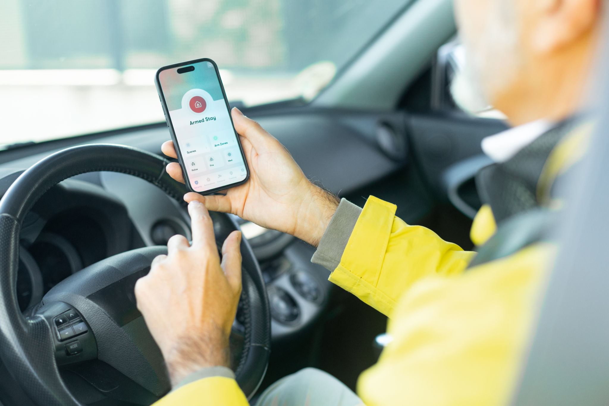 Driver using a mobile phone application to activate the car alarm system before leaving the vehicle
